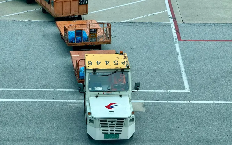 Air cargo dollies being moved on an airport apron